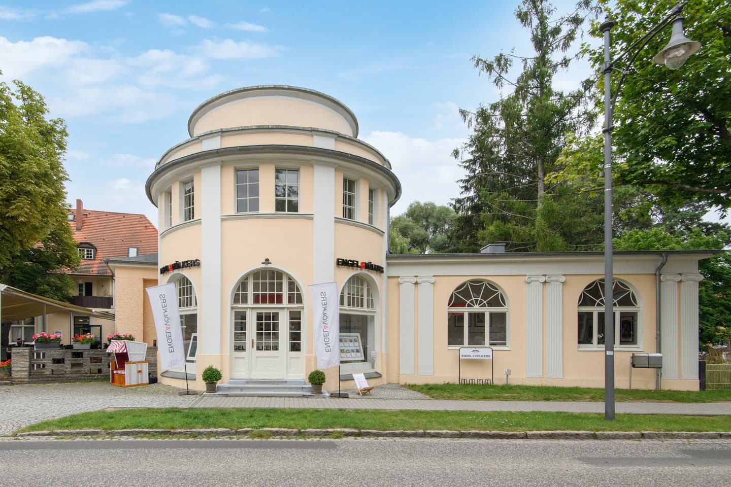 Engel & Völkers real estate office with a round tower design. A red and white striped beach chair sits outside.