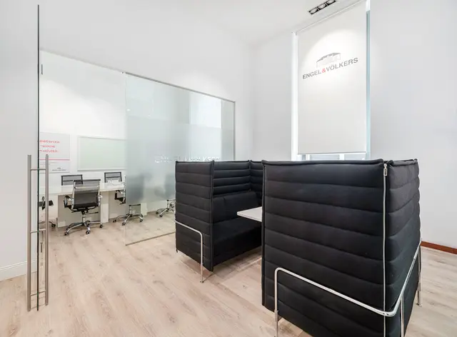 Engel & Völkers office interior with black booth seating, glass-walled conference room, and light wood floors.